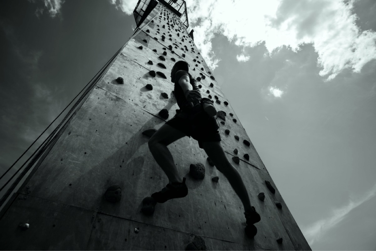 A climber on a steep climbing wall seen from below